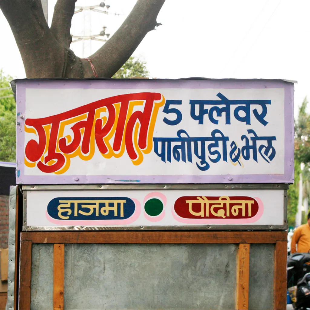 Handpainted sign on a food cart in Udaipur with a curved headline.